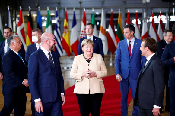 21일(현지시간) 앙겔라 메르켈(가운데) 독일 총리가 벨기에 브뤼셀에서 열린 유럽연합(EU) 정상회의에서 샤를 미셸(왼쪽) EU 정상회의 상임의장, 에마뉘엘 마크롱(오른쪽) 프랑스 대통령 등에게 둘러싸여 웃음 짓고 있다. 이날 회의에서 26개 회원국 정상들은 현안 논의에 앞서 퇴임을 앞둔 메르켈 총리를 위해 환송 행사를 열고 기립박수로 작별 인사를 했다. 브뤼셀 로이터 연합뉴스