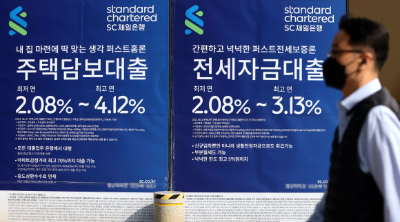 금융당국이 ‘가계부채 관리 강화 방안’을 발표한 26일 한 시민이 서울의 시중은행이 붙인 주택담보대출·전세자금대출 상품 광고 앞을 지나가고 있다. 연합뉴스