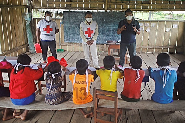지난달 12일 페루 아마존 원시 우라리나족이 사는 망구알 마을을 찾은 국제 적십자사 회원과 보건 관계자들이 부족 어린이들에게 코로나19를 설명하고 있다./로이터 연합뉴스