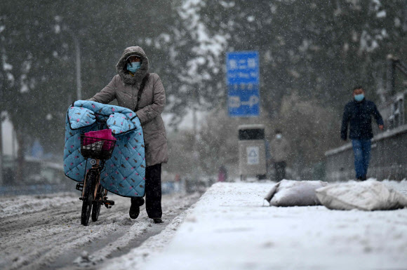 시민들이 7일(현지시간) 때이른 눈이 내린 중국 베이징 거리를 걷고 있다. AFP 연합뉴스
