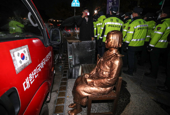 9일 오전 6시께 서울 종로구 옛 일본대사관 앞에서 ‘자유연대’를 비롯한 시민단체 회원들이 일본군 위안부 문제 관련 집회를 하기 위해 평화의 소녀상으로 진입을 시도하며 소녀상을 지키며 철야 시위를 벌이던 ‘반일행동’ 회원들과 마찰을 빚었다. 이에 평화의 소녀상 보호와 질서 유지를 위해 출동한 경찰이 소녀상 앞으로 진입을 시도하는 ‘자유연대’ 회원들의 진입을 저지했다.  사진은 경찰과 자유연대 측에서 동원한 집회 차량에 갇힌 평화의 소녀상. 2021.11.9  연합뉴스