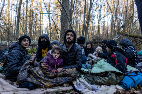 9일(현지시간) 폴란드-벨로루시 국경 근처 폴란드 나레프카 인근 숲에서 머물고 있는 이라크 도후크 출신 쿠르드족 가족의 모습. 생후 5개월 막내를 포함한 3대 16명의 가족은 약 20일 동안 숲속에서 지내다가 벨로루시로 8번이나 밀려났다. AFP 연합뉴스