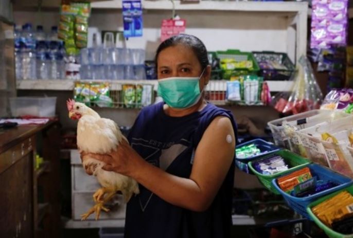인도네시아 서부자바주 치안주르의 한 마을 주민들이 신종 코로나바이러스 감염증(코로나19) 백신을 맞은 뒤 선물로 받은 생닭을 들고 있는 모습.