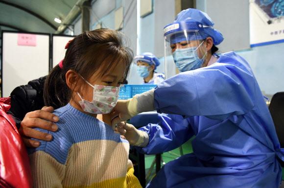 지난 13일 중국 베이징 하이뎬구의 한 종합병원에서 여자 어린이(왼쪽)가 코로나19 백신을 맞으며 금방이라도 울음을 터뜨릴 표정을 짓고 있다. 중국 정부는 3~11세 아동에 대한 백신 접종을 개시했다. 베이징 신화 연합뉴스