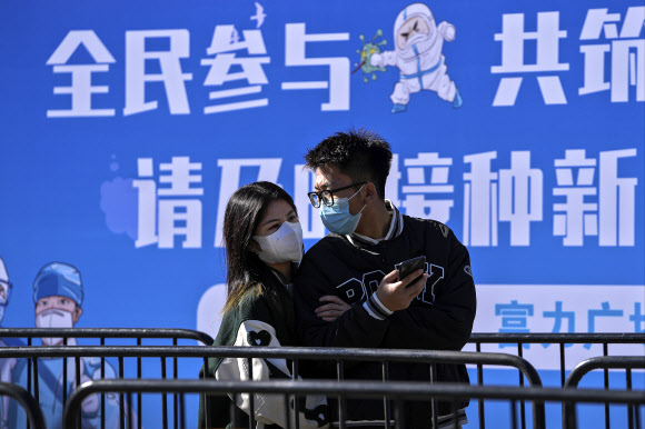중국 수도 베이징의 신종 코로나바이러스 감염증(코로나19) 백신 접종소 앞에서 10일 마스크를 쓴 남녀 한 쌍이 코로나19 부스터샷을 맞기 위해 차례를 기다리고 있다. 2021-11-10 베이징 AP 연합뉴스
