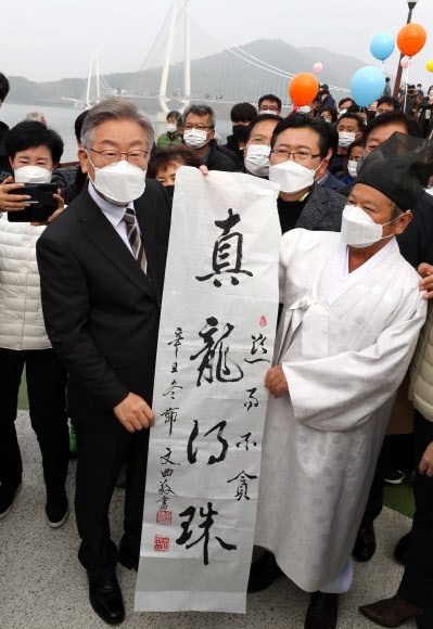 더불어민주당 이재명 대선후보가 20일 오전 충남 논산시 부적면 탑정호 출렁다리 앞에서 지역 유생인 김용주씨로부터 ‘진용득주(眞龍得珠. 진짜 용이 여의주를 얻는다)’ 글씨를 받고 있다. 2021.11.20  연합뉴스