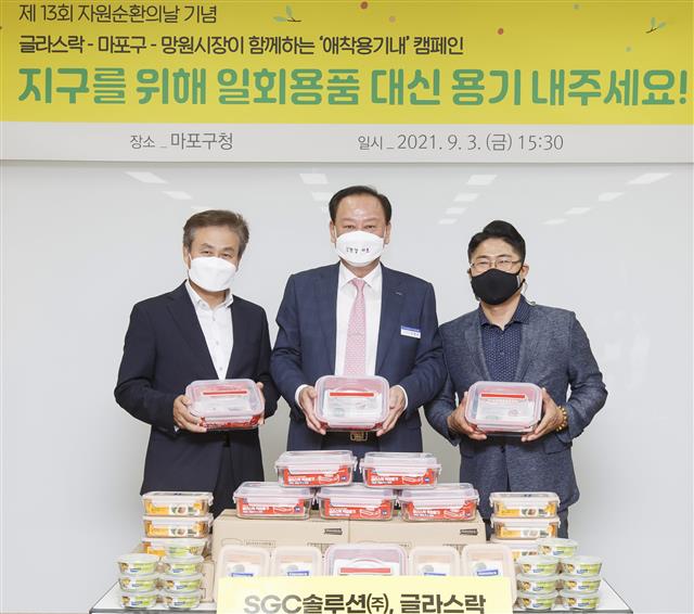 지난 9월 ‘제13회 자원순환의 날’을 맞아 유 구청장(가운데)과 김진철(오른쪽) 망원시장상인회장, 다회용기를 후원한 밀폐용기 브랜드 글라스락의 제조업체인 SGC솔루션의 임광빈 생활용품사업본부장과 기념사진을 찍고 있다.<br>마포구 제공