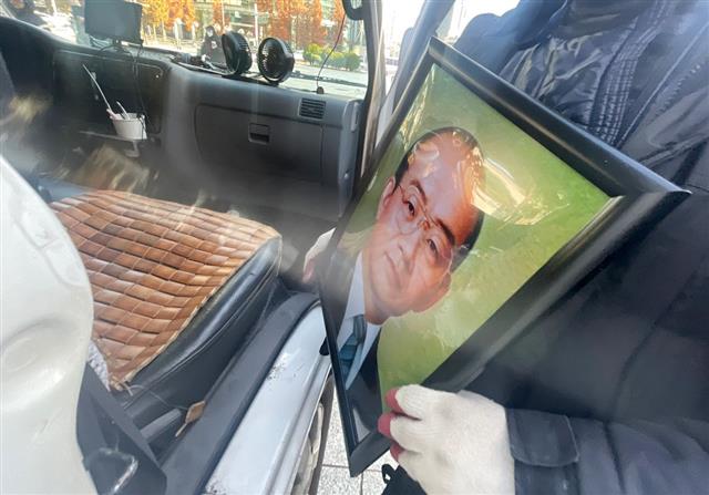 보수 성향 단체인 태극기혁명국민운동본부 회원이 24일 오전 서울 종로구 보신각 앞에서 전두환 전 대통령의 영정 사진을 차량으로 옮기고 있다. 이날 태극기혁명국민운동본부가 보신각 앞에 설치한 전 전 대통령의 추모 분향소는 철거됐다. 종로구청은 전 전 대통령의 분향소 설치를 준비 중이던 단체 측에 도로법 위반으로 금지를 통보했었다. 2021.11.24 뉴스1