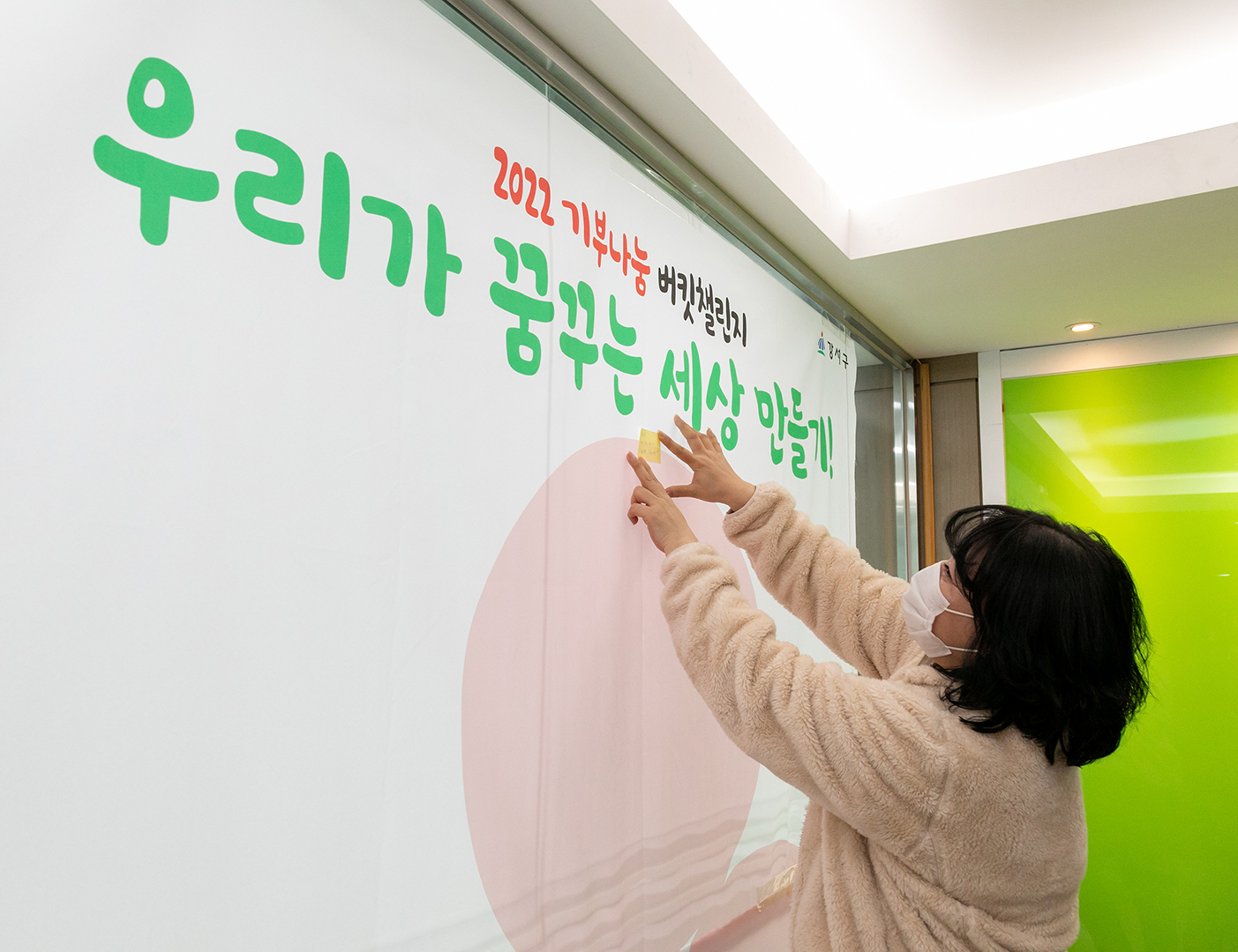 서울 강서구가 내년 2월까지 진행하는 기부 나눔 버킷 챌린지 참가자가 현판에 희망 메시지를 붙이는 모습. 강서구 제공 