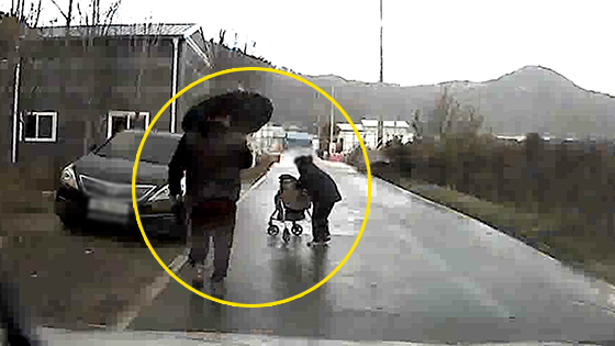 전씨가 지난 11일 오후 3시쯤 청주시 흥덕구 오송읍 공복리의 시골길에서 비를 맞고 걸어가는 할머니에게 우산을 건네기 위해 뛰어가고 있다. [사진=전희룡씨 제공]