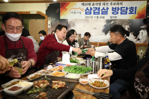 국민의힘 윤석열 대선 후보가 30일 저녁 충북 청주시 상당구 서문시장 한 음식점에서 상인들과 만나 삼겹살을 먹으며 환담하고 있다. 2021.11.30  사진공동취재단