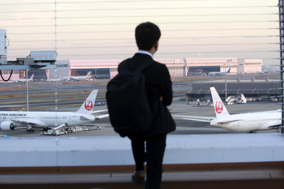일본 정부가 1일 자국을 목적지로 한 국제 항공편 탑승권 발매를 중단하도록 항공사들에 요청하는 초강수 대책을 내놓았다. 사진은 지난달 29일 나리타 국제공항 탑승장에서 활주로를 바라보는 한 남성. AP 자료사진 연합뉴스 