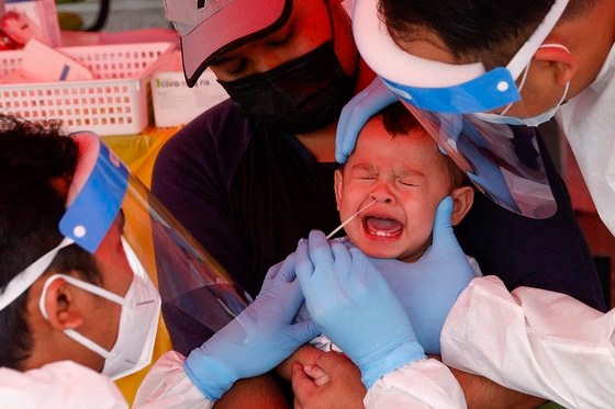 말레이시아의 한 의료센터에서 의료진이 유아의 콧속에서 코로나19 검체를 채취하고 있다. 연합뉴스