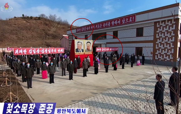 북한 평안북도에서 지난 5일 젖소 목장 준공식이 열렸다고 조선중앙TV가 6일 보도했다. 준공식에 쓰인 붉은색 팻말에 ‘위대한 김일성-김정일 주의’라는 표현과 함께 ‘위대한 김정은 동지’(붉은 원)라는 표현이 사용됐다. 북한은 최근 김정은 국무위원장에게 ‘수령’에 이어 ‘위대한’이라는 수식어를 사용하며 김 위원장의 정치적 위상을 강화하고 있다.  2021.12.6  조선중앙TV 화면