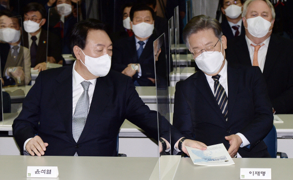 9일 오후 서울 마포구 연세대학교 신촌캠퍼스 김대중도서관에서 열린 김대중 대통령 노벨평화상 수상 21주년 기념식에서 국민의힘 윤석열 대선후보가 더불어민주당 이재명 대선후보에게 기념식과 관련한 안내책자를 전해주고 있다.2021. 12. 9 정연호 기자 tpgod@seoul.co.kr