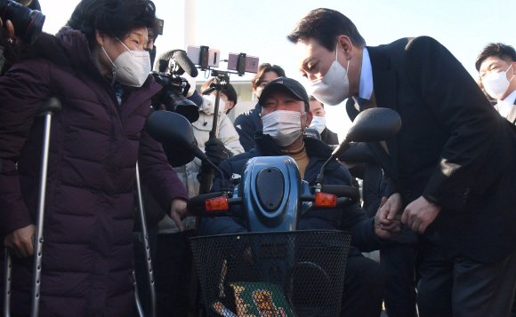 윤석열 국민의힘 대선후보가 13일 서울 여의도 국회 본관 앞에서 중앙선대위 장애인복지지원본부가 개최한 전국 릴레이정책투어 ‘장문현답(장애인 문제의 답은 현장에 있다)’ 출정식에 참석해 참석자들과 대화를 나누고 있다.2021.12.13 김명국선임기자 daunso@seoul.co.kr