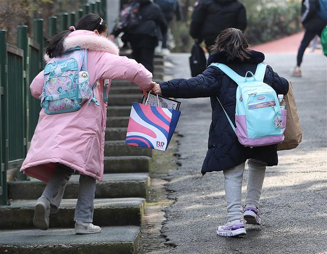 국내 코로나19 확산세가 거세지면서 전면등교 시행도 한 달을 못 채우고 중단됐다. 교육부는 16일 정부 거리두기 강화 조치에 따라 “지역 감염 위험이 큰 수도권 지역 모든 학교와 비수도권 과대학교?과밀학급을 중심으로 학교밀집도를 3분의 2 수준으로 조정한다”고 밝혔다. 지난달 22일 전국에서 전면등교가 시행된 지 24일 만이다. 16일 서울의 한 초등학교에서 아이들이 하교하고 있다. 2021.12.16  뉴스1