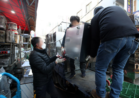 정부가 코로나19 특별방역 대책으로 매출이 감소한 소상공인 320만명에게 100만원 상당의 방역지원금을 지급하기로 했다.  이·미용업, 키즈카페 등 인원·시설 이용 제한업종 12만곳은 소상공인 손실보상 대상에 새로 포함된다.  정부는 이런 내용 등을 담은 방역지원금 및 손실보상·지원 확대 방안을 17일 발표했다.  사진은 이날 서울 중구 황학동주방가구거리에서 폐업한 가게에서 나온 집기류 등을 내리고 있다. 2021.12.17 연합뉴스