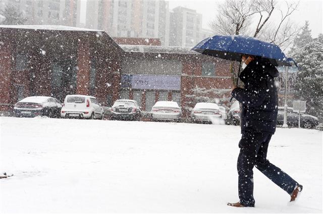 17일 오후 광주 서구 농성동 일대에서 한 시민이 눈을 피해 이동하고 있다. 2021.12.17 뉴스1
