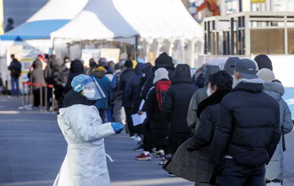 질병관리청에서 관리하는 코로나19 선별검사 시스템 접속에 문제가 생긴 18일 서울역 광장에 마련된 임시 선별검사소에서 관계자가 대기하는 시민들에게 관련 내용을 전달하고 있다. 2021.12.18  연합뉴스