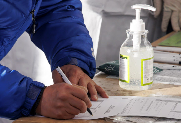 질병관리청에서 관리하는 코로나19 선별검사 시스템 접속에 문제가 생긴 18일 서울역 광장에 마련된 임시 선별검사소에서 시민들이 접수를 위해 수기로 관련 설문지를 작성하고 있다. 2021.12.18  연합뉴스