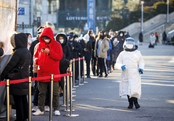 질병관리청에서 관리하는 코로나19 선별검사 시스템 접속에 문제가 생긴 18일 서울역 광장에 마련된 임시 선별검사소에서 관계자가 해당 내용을 시민들에게 설명하기 위해 분주하게 움직이고 있다. 2021.12.18  연합뉴스