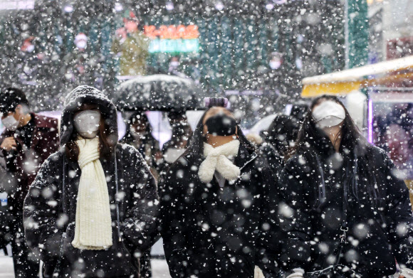 18일 오후 서울 홍대거리에서 시민들이 눈을 맞으며 길을 걷고 있다. 2021.12.18  연합뉴스