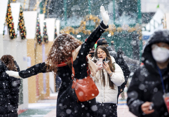 18일 오후 서울 홍대거리에서 외국인들이 눈을 맞으며 사진을 찍고 있다. 2021.12.18  연합뉴스