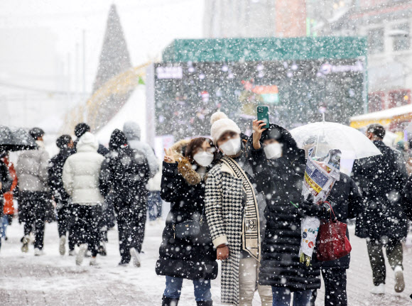 18일 오후 서울 홍대거리에서 시민들이 눈을 맞으며 사진을 찍고 있다. 2021.12.18  연합뉴스