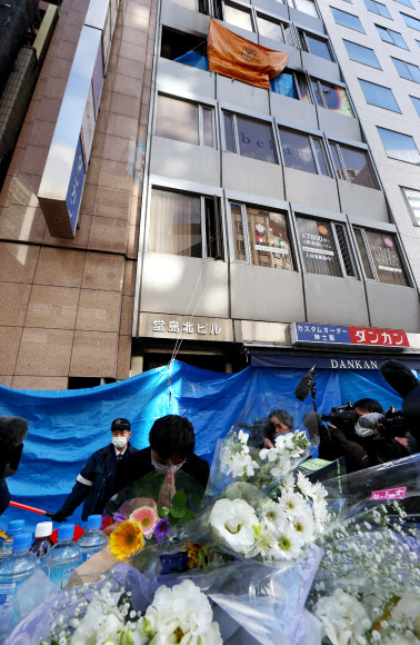 24명의 목숨을 앗아 간 일본 오사카시 빌딩 화재 현장 앞에 지난 18일 희생자를 추모하는 꽃이 놓여 있다. 현지 경찰은 전날 이 상가 건물 4층 병원에서 발생한 화재 사건의 방화 용의자로 해당 병원에서 통원 치료를 받은 다니모토 모리오(61)를 확정했다. 오사카 지지통신 AFP 연합뉴스