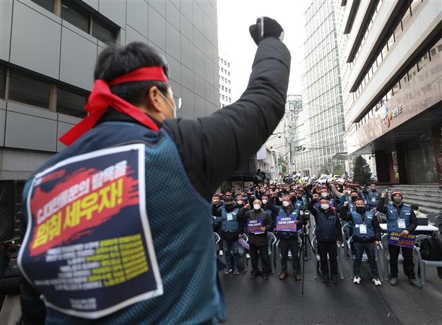 20일 오후 서울 중구 CJ대한통운 본사 앞에서 열린 CJ대한통운 전국대표자 총파업 선포대회에서 참가자들이 구호를 외치고 있다. CJ 대한통운 택배노조가 오는 28일부터 무기한 총파업에 나선다. 택배노동자들은 CJ대한통운이 택배노동자들의 과로사를 막기 위해 국민들이 합의해 준 택배요금 인상액의 4800억원 중 3500억원을 자기 초과 이윤으로 가져가고 있으며 저상탑차 문제에 대한 해결 의지가 없다고 주장했다. 2021.12.20  뉴스1