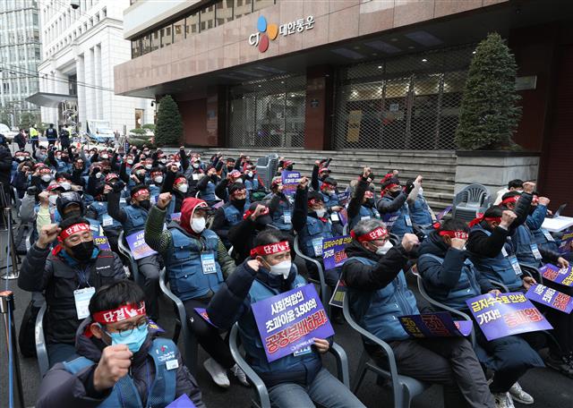 20일 오후 서울 중구 CJ대한통운 본사 앞에서 열린 CJ대한통운 전국대표자 총파업 선포대회에서 참가자들이 구호를 외치고 있다. CJ 대한통운 택배노조가 오는 28일부터 무기한 총파업에 나선다. 택배노동자들은 CJ대한통운이 택배노동자들의 과로사를 막기 위해 국민들이 합의해 준 택배요금 인상액의 4800억원 중 3500억원을 자기 초과 이윤으로 가져가고 있으며 저상탑차 문제에 대한 해결 의지가 없다고 주장했다. 2021.12.20  뉴스1