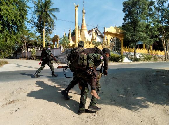 미얀마 군부에 저항하는 시민방위군(PDF) 전사가 19일 카인주의 마에 흐토 탈라이에서 미얀마군과 교전 중 다치자 동료의 등에 업혀 후송되고 있다. 마에 흐토 탈라이 로이터 연합뉴스 