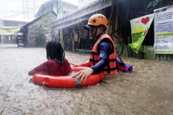 지난 16일(현지시간) 필리핀 남부 카가얀데오로에서 구조대원이 홍수를 뚫고 한 소녀를 구하고 있다. 카가얀데오로 필리핀 해안경비대 제공 AP 연합뉴스