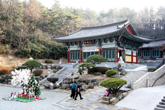 크리스마스를 앞둔 21일 경북 포항시 남구 연일읍 대한불교조계종 문수사 대웅전 앞마당에 세워진 크리스마스트리 옆으로 사찰 신도들이 지나가고 있다. 2021.12.21 연합뉴스