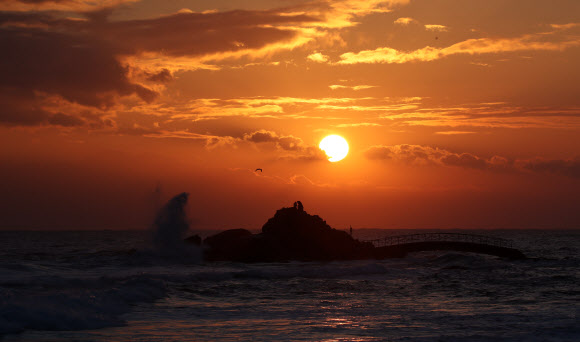 22일 강원 강릉시 사천해변 앞바다에서 높은 파도와 짙은 구름을 뚫고 붉은 해가 솟아오르고 있다. 2021.12.22 연합뉴스