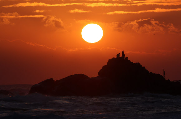 22일 강원 강릉시 사천해변 앞바다에서 높은 파도와 짙은 구름을 뚫고 붉은 해가 솟아오르고 있다. 2021.12.22 연합뉴스