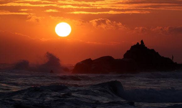 22일 강원 강릉시 사천해변 앞바다에서 높은 파도와 짙은 구름을 뚫고 붉은 해가 솟아오르고 있다. 2021.12.22 연합뉴스