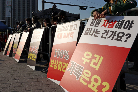 ‘코로나19 대응 전국자영업자비상대책위원회(자영업비대위) 정부 방역 대책 반대 총궐기 대회’가 열리는 22일 오후 서울 광화문시민열린마당에서 관계자들이 집회 시작 전 피켓 앞에 서 있다. 2021.12.22 연합뉴스