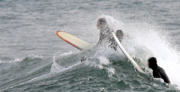 22일 강원 양양지역의 한 해변에서 서퍼들이 파도타기를 즐기고 있다.       2021.12.22 연합뉴스