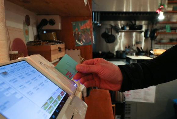 더불어민주당과 정부는 23일 연 매출 3억원 이하 가맹점에 대해 신용카드 수수료를 기존 0.8%에서 0.5%로 낮추기로 했다. 연 매출 30억원 이하 카드 가맹점 대상으로도 수수료가 조금씩 인하되며 전체 가맹점 가운데 96%가 수수료 인하 혜택을 볼 전망이다. 사진은 이날 서울 시내 한 식당에서 카드 결제하는 모습. 2021.12.23 연합뉴스