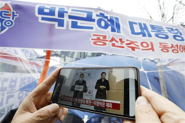 24일 오전 서울 중구 청계광장 인근에서 대한당 관계자가 박근혜 전 대통령 사면 관련 뉴스를 시청하고 있다. 정부는 2022년 신년을 앞두고 오는 31일자로 전직 대통령 등 3094명에 대한 특별사면을 단행한다고 24일 밝혔다. 박 전 대통령은 국정농단 등의 사건으로 지난 2017년 3월31일 구속돼 올해 1월 대법원에서 징역 20년과 벌금 180억원, 추징금 35억원이 확정됐다. 오는 31일 풀려나면 4년 9개월 만에 나오는 셈이다. 2021.12.24  뉴스1