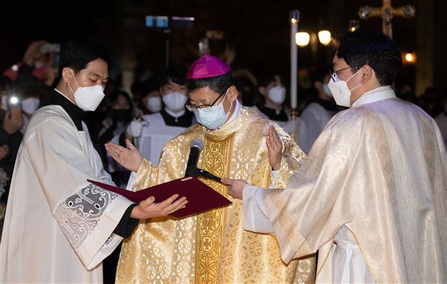정순택 서울대교구장 대주교가 25일 서울 명동성당 앞마당에서 아기 예수를 말구유에 안치하는 구유 예절의식을 하고 있다. 2021.12.25 뉴스1