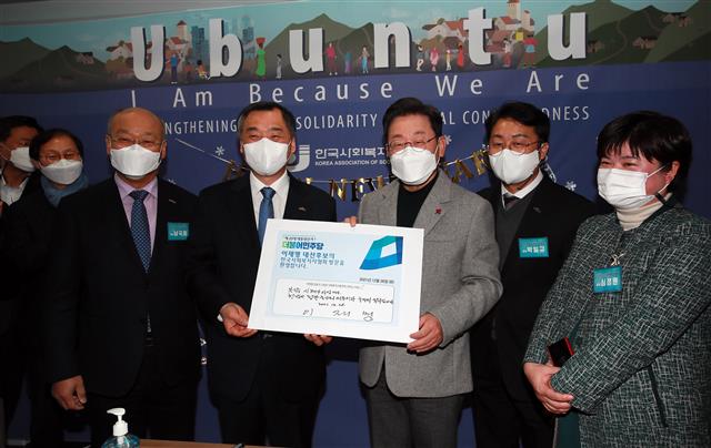 이재명(오른쪽 세 번째) 더불어민주당 대선후보가 28일 오전 서울 영등포구 문래동 한국사회복지사협회에서 열린 복지국가실천연대 간담회 ‘청년 그리고 사회복지사를 만나다’에 참석하며 오승환(오른쪽 네 번째) 한국사회복지사협회 회장 등과 기념촬영을 하고 있다. 방명록에는 ‘복지는 시혜가 아닙니다. 헌법이 정한 국가의 의무이자 국민의 권리입니다’라고 작성했다. 2021.12.28 국회사진취재단