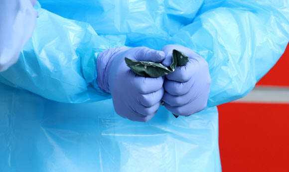 28일 경기도 성남시 국군수도병원 응급실 앞에서 한 의료진이 핫팩으로 잠시나마 추위를 녹이고 있다. 2021.12.28 연합뉴스