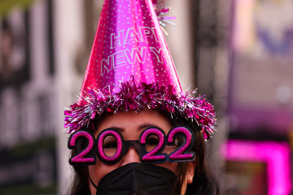 지난 20일(현지시간) 미국 뉴욕 맨해튼에서 새해 축하 행사를 앞두고 한 시민이 2022 숫자 안경을 쓰고 있다. 뉴욕 로이터 연합뉴스