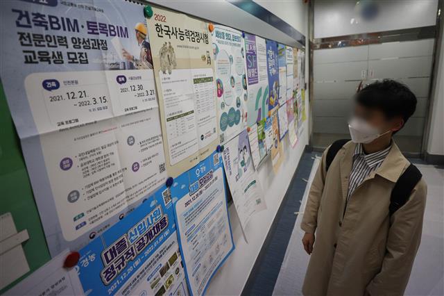 고질적인 취업난과 코로나19 사태까지 덮치면서 대학 졸업유예제를 찾는 학생들이 늘고 있다. 29일 교육부에 따르면, 2020년 고등교육기관(대학) 졸업자 취업률은 65.1%로 집계됐다. 2011년 이후 최저치다. 교육부 관계자는 통계치에 대해 “2020년 2월 졸업한 학생들의 취업률이 이렇게 낮은 것은 코로나19 영향이 가장 큰 것으로 보인다”고 말했다. 졸업유예 제도는 학점 등 졸업에 필요한 요건을 갖춘 ‘수료’ 상태에서 졸업 시기만 연기해 학사 학위 취득을 유예하는 제도다.  사진은 서울의 한 대학교 취업게시판에서 채용정보를 살펴보는 대학생 모습. 2021.12.29 뉴스1