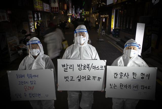 올해도, 여전히 신종 코로나바이러스 감염증(코로나19)의 한해였다. 백신 접종률이 높아짐에 따라 일상 회복에 대한 기대감이 높았지만 연이은 돌파 감염에 오미크론 변이까지 발생하며 위드코로나는 요원해지고 있다. 의료진이 네온사인이 빛나는 종로 유흥가에 새해 소원을 들고 섰다. 이들은 공공운수노조 의료연대본부 소속 김민정 간호사(왼쪽부터)와 김별샘 병원노동자, 김혜정 간호사다. 새해 소망을 화이트보드에 적어달라는 부탁에 코로나19가 내년에도 끝나지 않을 것 같다고 말하면서도 마스크와 방호복을 벗고 싶다고 적었다. 친구들을 자유롭게 만나거나 해외여행을 가고 싶지 않냐는 질문에는 개인적 소망보다 코로나19 현장에서의 구조적 문제를 해결하고 싶다고 말했다. 간호사 한 명에게 주어진 환자가 너무 많아 식사와 화장실을 포기하면서까지 바쁘게 뛰어다니지만 결국에는 환자를 제대로 간호하지 못했다는 죄책감에 시달리게 되고, 묵묵히 일하던 동료가 결국 환자 곁을 떠나게 되는 일이 발생하고 있다며 아쉬움을 드러냈다. 다가오는 2022년 임인년(壬寅年)에는 의료진들이 바라는 것처럼 의료진이 환자들에게 전념할 수 있는 한해가 되길 바란다고 희망했다.