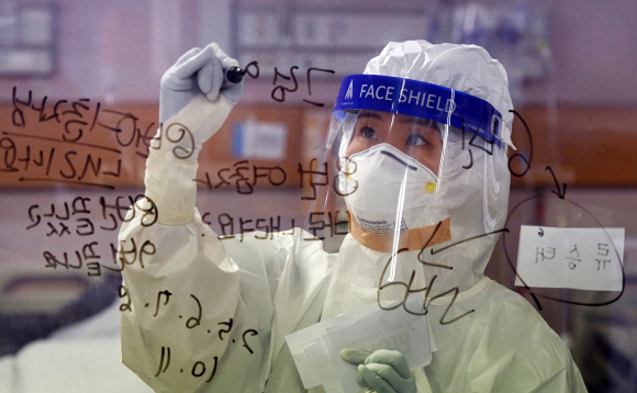 중환자실의 한 간호사가 유리창에 글을 쓰며 의사소통을 하고 있다.