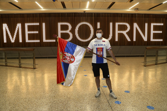남자 테니스 선수 노바크 조코비치(세르비아)의 팬이 6일 호주 멜버른 국제공항 입국장에서 세르비아 국기를 들고 서 있다. 2022.1.6  AP 연합뉴스